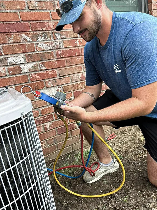 An Air Pro technician tests the refrigerant levels in an air conditioner.
